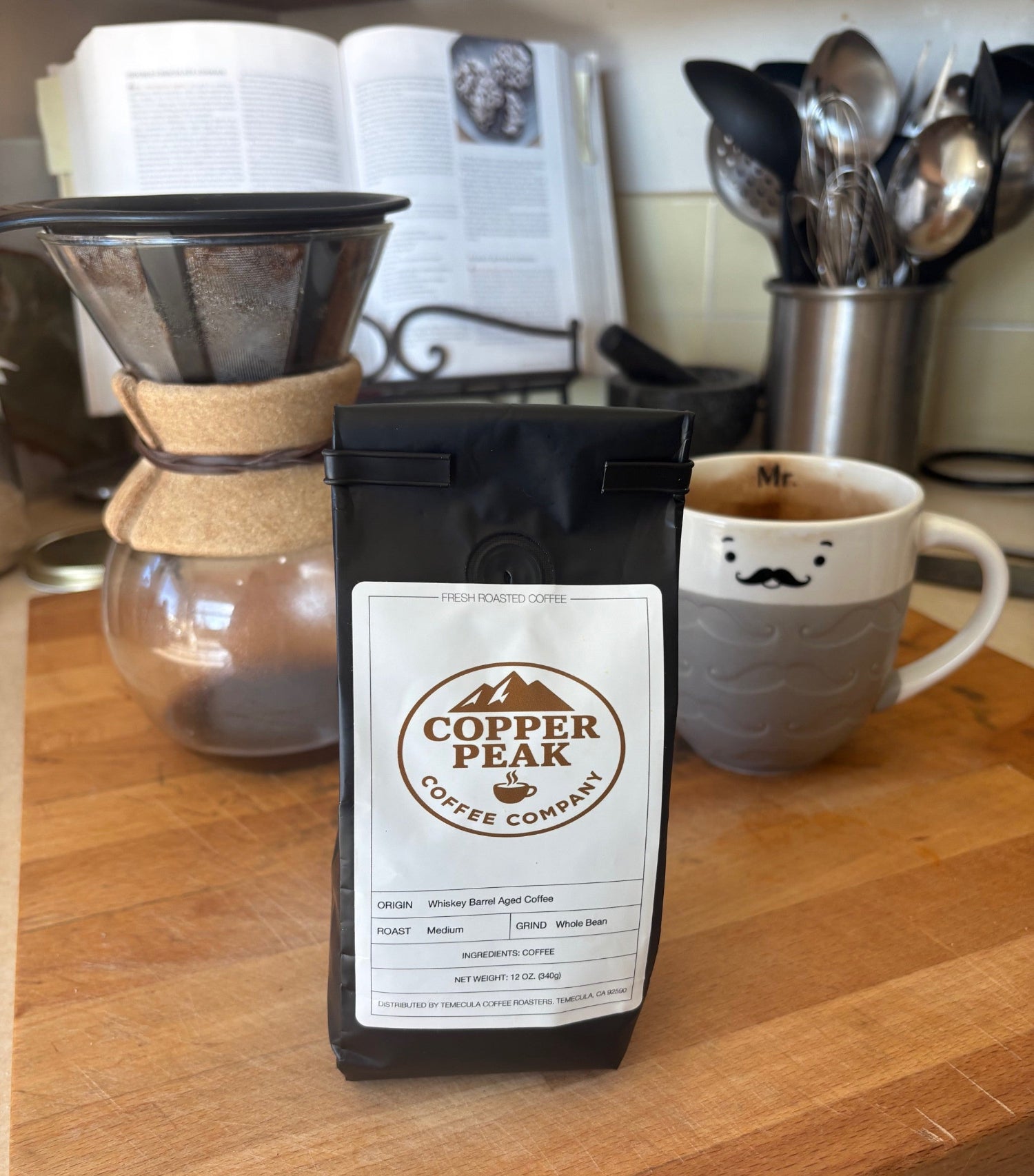 Copper Peak Coffee Company bag on a kitchen counter with coffee mug and Chemex in the background